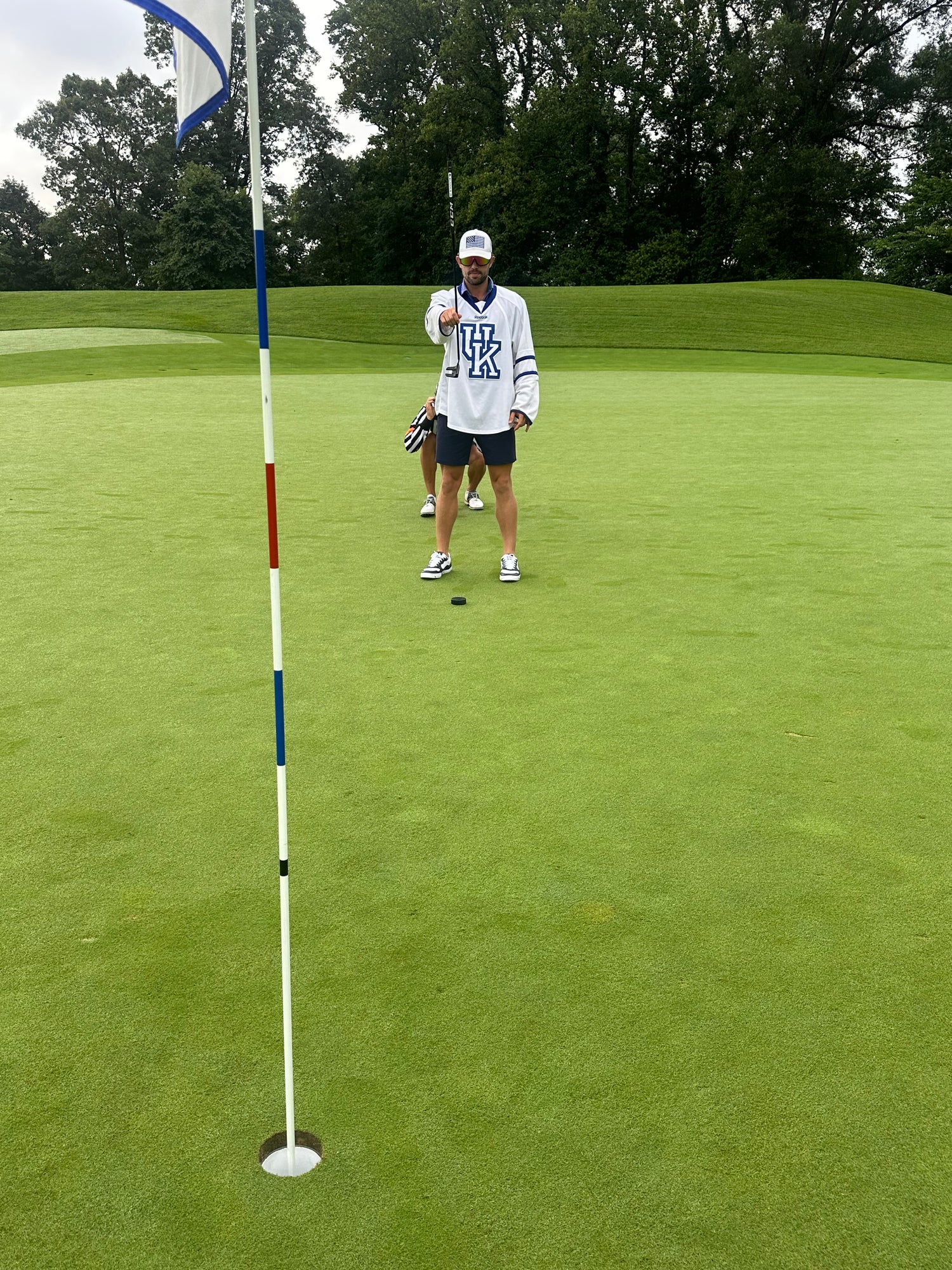 Person on a golf course with a flagstick in the foreground